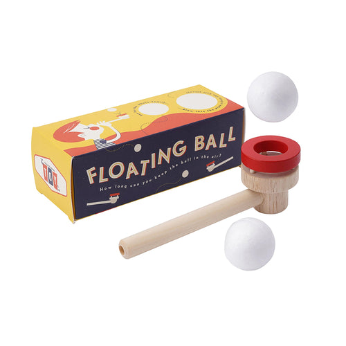 Floating ball toy with red top and wooden handle next to its packaging on a white background